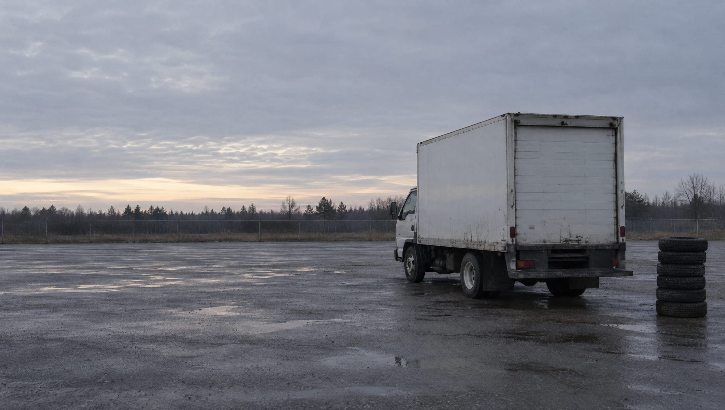 A box truck parked in an empty lot at dawn
