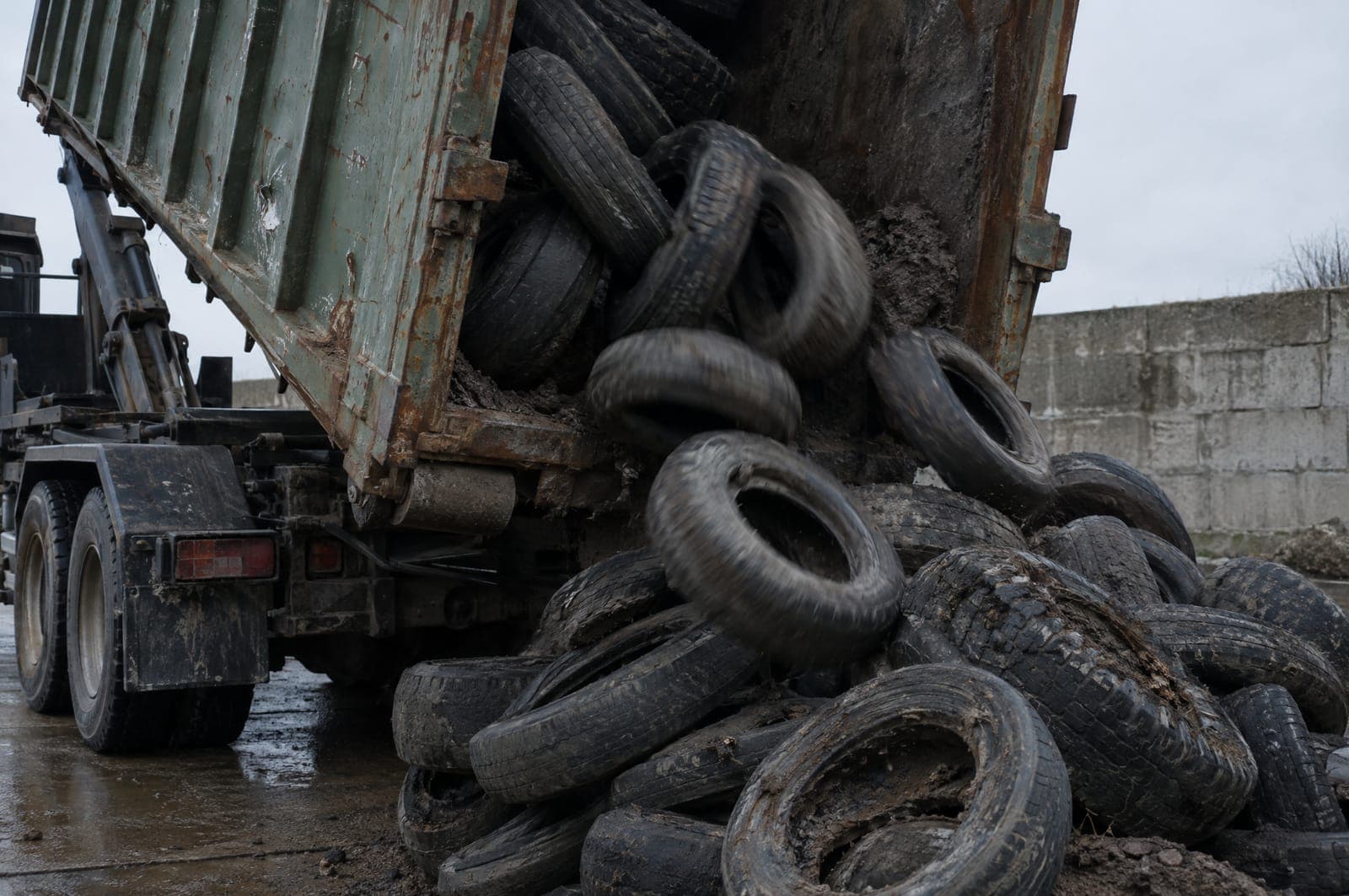 A roll-off container tipping a load of scrap tires